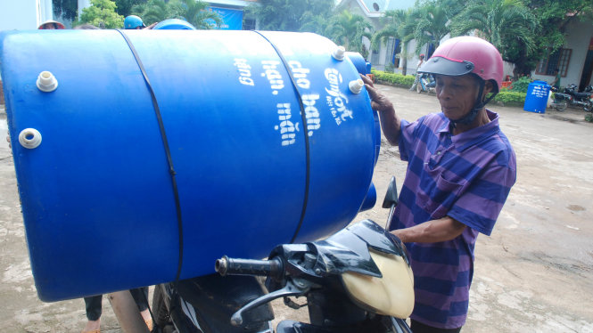 Người dân đưa bồn chứa nước sạch được tặng trở về gia đình - Ảnh: B.D