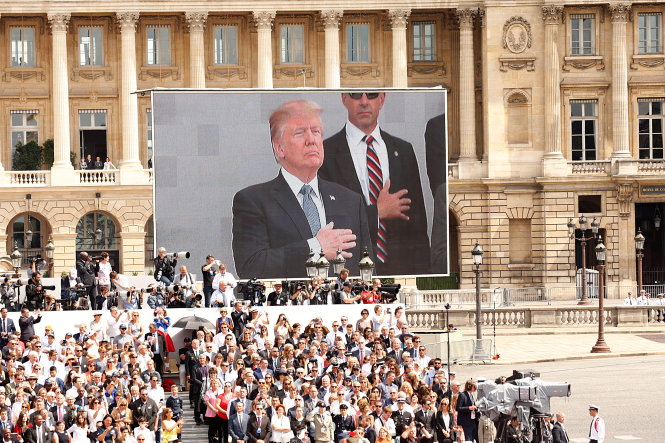 Hình ảnh tổng thống Trump lắng nghe Quốc ca Pháp được phát trên màn hình lớn ở Quảng trường Concorde - Ảnh: Reuters