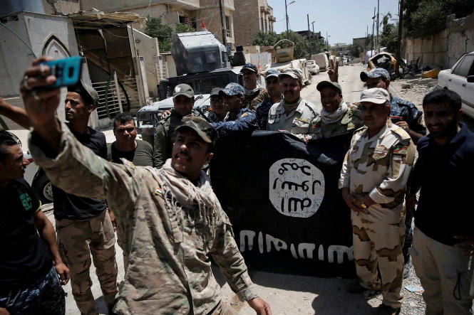 Binh sĩ Iraq chụp ảnh lưu niệm với lá cờ của khủng bố IS thu giữ được ở thành phố Mosul - Ảnh: Reuters