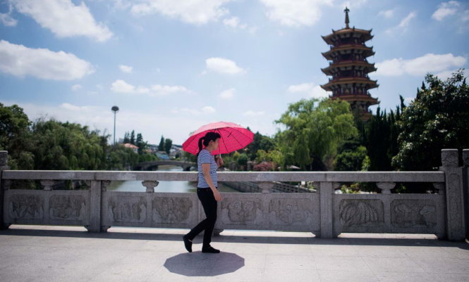 Một phụ nữ che dù đi trong nắng nóng gay gắt ở Thượng Hải - Ảnh: AFP