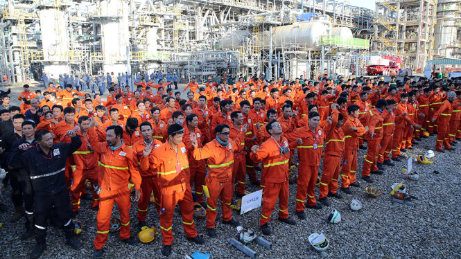 Công nhân Nhà máy Lọc dầu Dung Quất làm động tác khởi động thể dục trước khi vào làm việc - Ảnh: Trần Mai