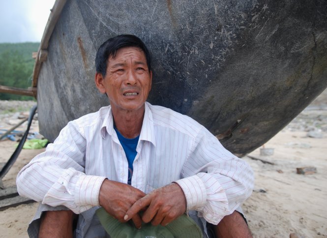 Ông Tưởng Văn Sơn (46 tuổi, trú thôn Thọ Sơn, xã Quảng Đông) ngồi thẩn thờ khi cả ba chiếc tàu của gia đình đều bị bão phá nát. May còn chiếc ghe còn khả năng sửa chữa - Ảnh: Quốc Nam