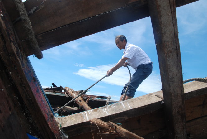Ông Nguyễn Cao Hóa, ngư dân trú thôn 19-5, xã Quảng Đông giúp kéo phần thân tàu còn lại của ngư dân bị chìm lên bờ - Ảnh: Quốc Nam