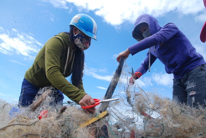 Lượm lặt những mảnh lưới rách để tận dụng lại - Ảnh: Quốc Nam