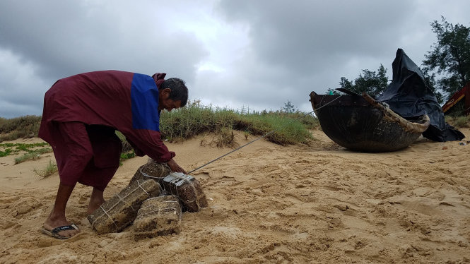 Ngư dân Lê Kỳ, 80 tuổi, trú thôn Nhân Tiến, xã Nhân Trạch, huyện Bố Trạch (Quảng Bình) buộc thêm đá vào ghe để chống gió bão - Ảnh: QUỐC NAM