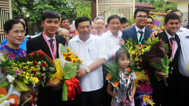 Ông Nguyễn Xuân Đường, chủ tịch UBND tỉnh Nghệ An tặng hoa chúc mừng 4 học sinh Trường THPT chuyên Phan Bội Châu giành được huy chương tại các kỳ thi Olympic quốc tế - Ảnh: DOÃN HÒA