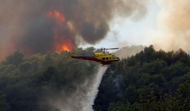 Trực thăng chữa cháy đang tưới nước xuống một đám cháy ở Carros, gần Nice Eric Gaillard - Ảnh: REUTERS