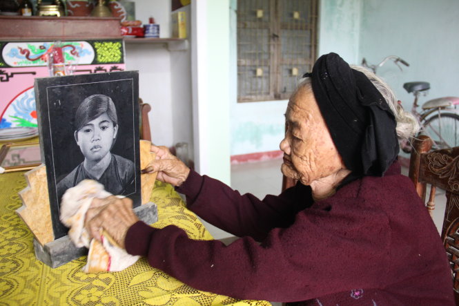 Mẹ Nhờ lau di ảnh con gái đầu - liệt sĩ Mai Thị Hai - Ảnh: TRƯỜNG TRUNG