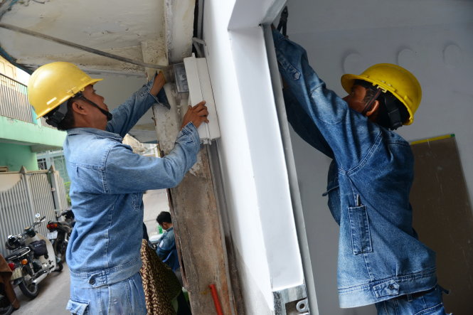 Nhân viên Công ty Điện lực Sài Gòn gắn điện kế mới cho một hộ dân trên đường Võ Văn Kiệt, Q.1, TP.HCM - Ảnh: QUANG ĐỊNH