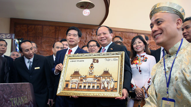 Ông Tất Thành Cang giới thiệu cách làm tranh và tặng bức tranh gạo cho ông SSinlavong Khutphaythun, Ủy viên Bộ Chính trị, Bí thư Thành ủy, Đô trưởng Thủ đô Viêng Chăn tại lễ khai mạc “Những ngày TP.HCM tại Viêng Chăn” - Ảnh: M.HOA