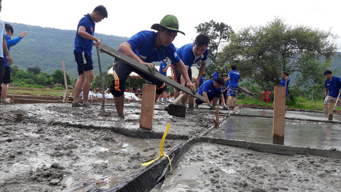 Các chiến sĩ tình nguyện Mùa hè xanh đang tiến hành đổ bê tông sân bóng chuyền tại trường tiểu học Nahaek - Ảnh: QUANG PHƯƠNG