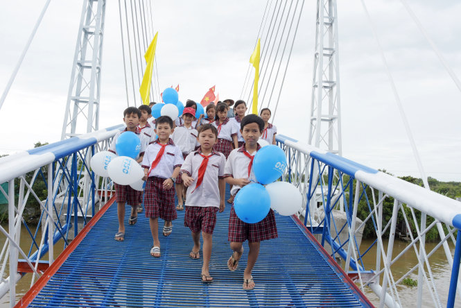 Các em học sinh bước những bước chân đầu tiên qua cầu Giang Sơn - Ảnh: MINH ĐỨC