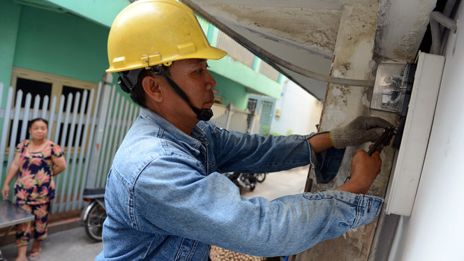 Nhân viên Công ty Điện lực Sài Gòn gắn mới điện kế cho một hộ dân trên đường Võ Văn Kiệt, Q.1, TP.HCM - Ảnh: Quang Định