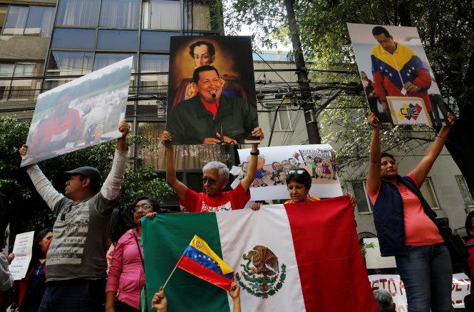 Những người Venezuela ủng hộ tổng thống Maduro giương cao ảnh của cố tổng thống Hugo Chavez - Ảnh: REUTERS