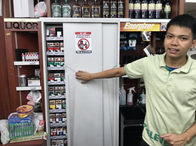 Nhân viên cửa hàng tiện lợi 7Eleven giới thiệu cửa tự động đóng để che thuốc lá bên trong - Ảnh: LÊ NAM