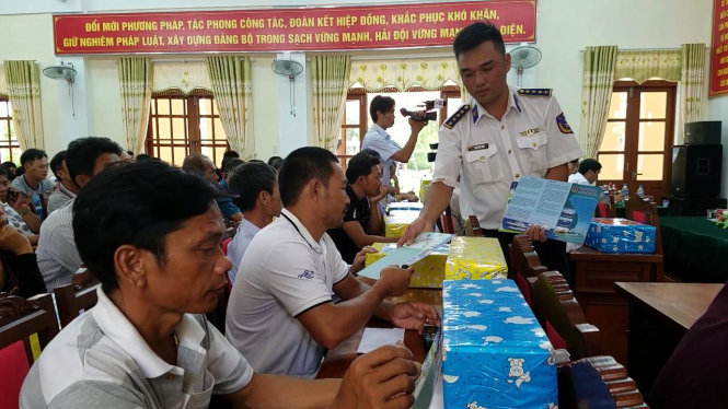 Cán bộ vùng cảnh sát biển 2 phát tờ rơi tuyên truyền về luật biển cho ngư dân xã Triệu An - Ảnh: QUỐC NAM