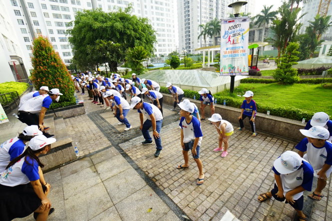 Đoàn đi bộ khởi động làm nóng cơ thể trước khi xuất phát đi bộ xung quanh khu căn hộ cao cấp Giai Việt trên đường Tạ Quang Bửu, Q.8, TPHCM trong chương trình 10.000 bước chân thay đổi cuộc sống sáng 6-8 - Ảnh: QUANG ĐỊNH