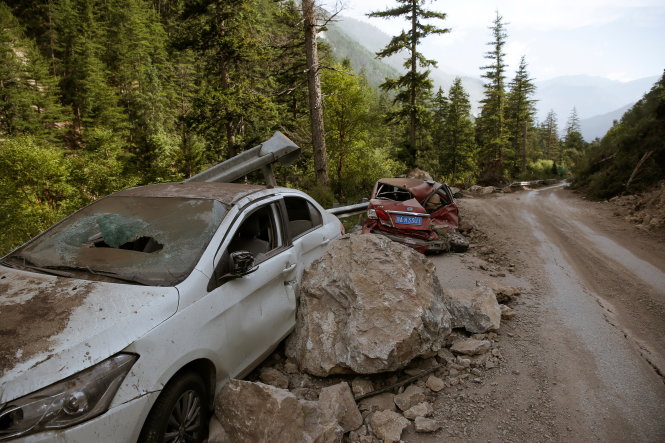 Xe hơi của người dân bị đá núi hất văng vào bên vệ đường - Ảnh: REUTERS