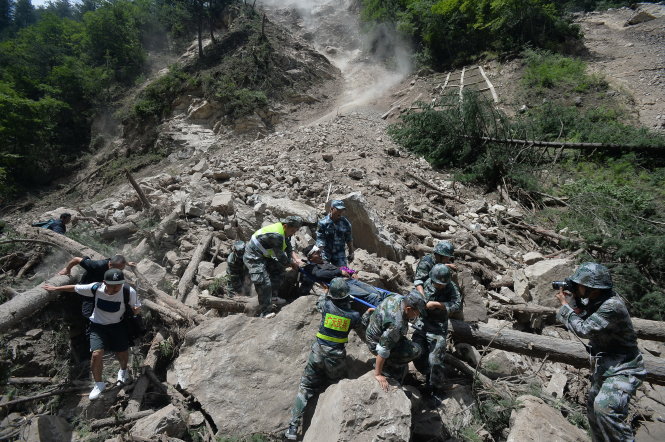 Lực lượng cứu hộ phải làm việc vất vả trong điều kiện địa hình ngổn ngang đất đá - Ảnh: REUTERS