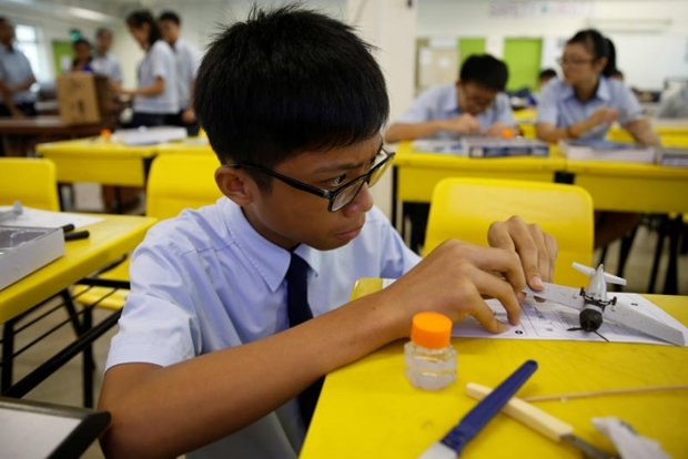 Một em nhỏ đang lắp ráp mô hình máy bay trong lớp học ở Singapore - Ảnh: Reuters