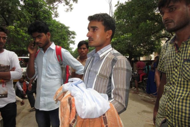 Thân nhân một đứa trẻ tử vong đứng trước cổng bệnh viện Baba Raghav Das ngày 11-8 - Ảnh: AFP