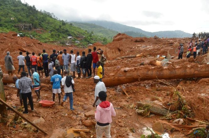 Người dân đi cùng đoàn cứu hộ sau một vụ lở đất ở Sierra Leone - Ảnh: Reuters
