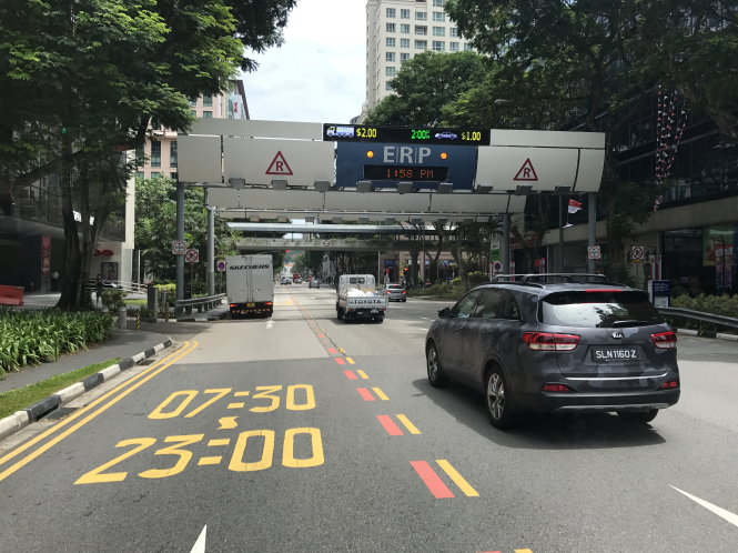 Xe cộ chuẩn bị vào khu vực đường Jalan Besar có ERP với mức giá hiển thị trên bảng điện tử: bên trái là mức 2 SGD cho xe buýt lớn, xe tải tải trọng nặng; bìa phải là giá ô tô con, taxi: 1 SGD trong khung giờ từ 12h05 cho đến 14h - Ảnh: LÊ NAM