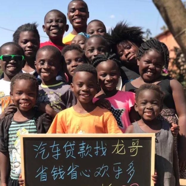Những đứa trẻ châu Phi cầm một tấm bảng quảng cáo các sản phẩm và dịch vụ tại Trung Quốc - Ảnh: từ Taobao