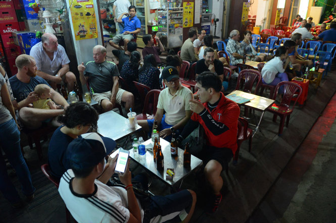 Du khách nước ngoài ngồi uống bia trên vỉa hè phố đi bộ Bùi Viện tối 20-8 - Ảnh: QUANG ĐỊNH