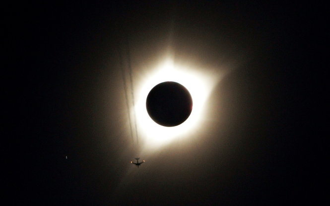 Một chiếc máy bay phản lực lượn cánh trên nền trời tối của hiện tượng nhật thực ở Guernsey, Wyoming - Ảnh: REUTERS
