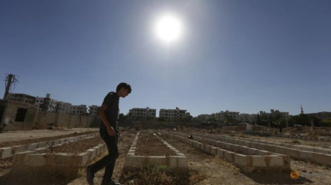 Một người đàn ông đi bộ dọc các ngôi mộ tập thể của những nạn nhân trong vụ tấn công hóa học ở Zamalka, ngoại ô Damascus hồi tháng 8-2014 - Ảnh: Reuters