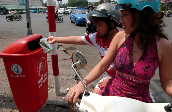 Mẹ dừng xe và dạy con bỏ rác vào thùng (ảnh chụp trên đường Huỳnh Thúc Kháng, Q.1, TP.HCM) - Ảnh: NGUYỄN CÔNG THÀNH
