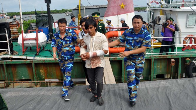 Dìu, đưa ngư dân Trần Thanh Minh lên bờ để tiếp tục chữa trị - Ảnh: ĐÔNG HÀ