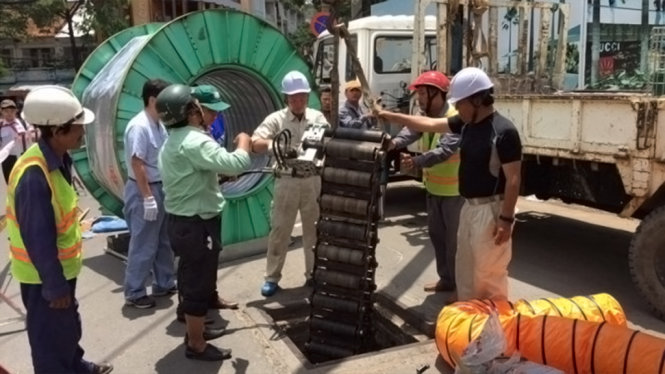 Các kỹ sư Nhật đưa thiết bị quấn lá thép xuống hố ga phục vụ thi công sửa chữa cống thoát nước khu vực vòng xoay Cống Quỳnh - Nguyễn Cư Trinh, Q.1 - Ảnh: LAI QUỐC HUY