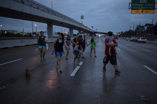 Gia đình họ Dương bồng bế nhau đi bộ dọc xa lộ liên tiểu bang Interstate 45 trong lúc tháo chạy khỏi cơn bão Harvey ở Houston, bang Texas - Ảnh: Reuters