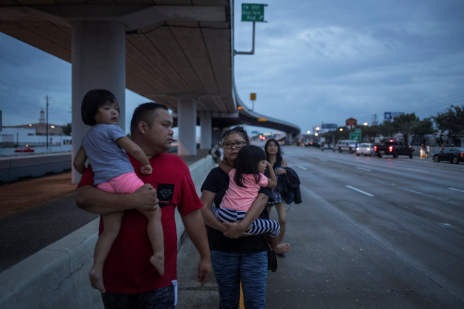 Một gia đình họ Dương bồng bế nhau đi bộ dọc xa lộ liên tiểu bang Interstate 45 trong lúc tháo chạy khỏi cơn bão Harvey ở Houston, bang Texas - Ảnh: Reuters