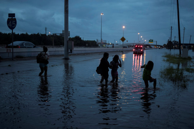 Các thành viên trong gia đình họ Duong lội qua khu nước ngập ở Houston, bang Texas - Ảnh: REUTERS