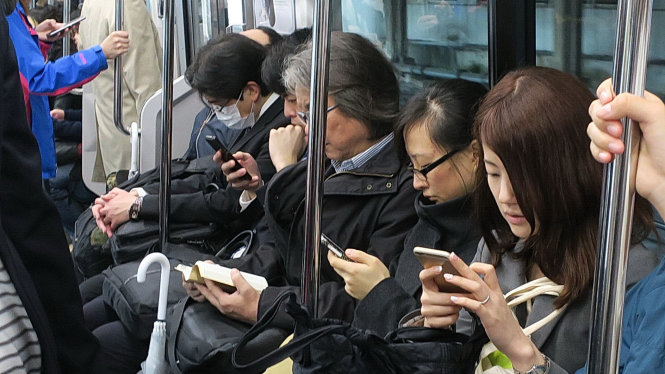 Nhiều người trẻ thế hệ iGen sử dụng smartphone trên xe điện ngầm ở Tokyo -  Ảnh: T.T.D.