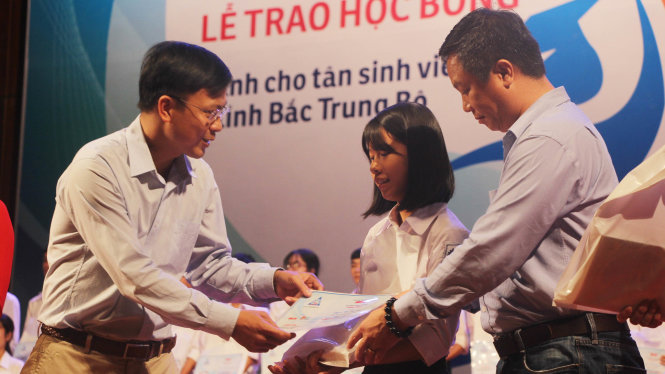 Ông Phan Văn Đắc, trưởng ban công tác xã hội báo Tuổi Trẻ trao học bổng cho các bạn tân sinh viên - Ảnh: DOÃN HÒA