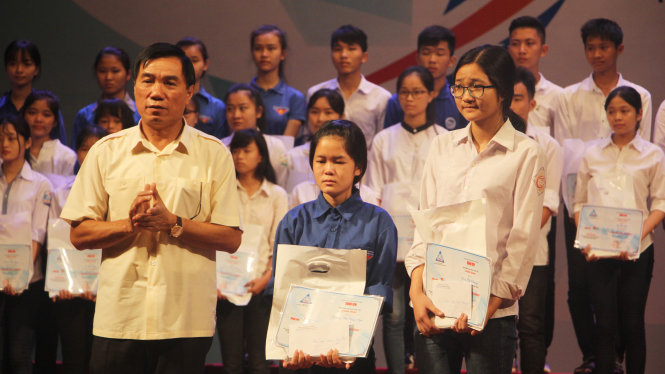 Ông Phạm Đăng Quyền, phó chủ tịch UBND tỉnh Thanh Hóa trao hai suất học bổng cho hai bạn Linh và Minh - Ảnh: DOÃN HÒA