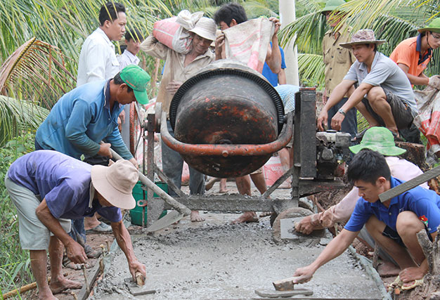 Chiến sĩ ĐH Công nghệ TP.HCM và người dân cùng làm đường bêtông tại huyện Thạnh Phú trong Mùa hè xanh 2014 - Ảnh: Q.Linh