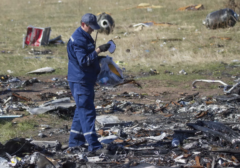 Một điều tra viên quốc tế xem xét hiện trường vụ máy bay rơi Ảnh: Reuters