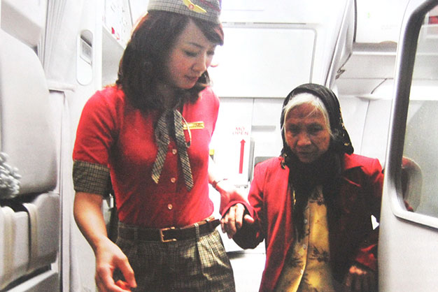 Nữ TVHK hỗ trợ hành khách lớn tuổi xuống máy bay - Ảnh: VJA