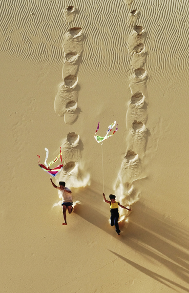 Hai cậu bé vui chơi thả diều trên một đồi cát ở Bình Thuận đoạt giải nhì ở hạng mục “Khoảnh khắc” thuộc về tác giả Lý Hoàng Long, Việt Nam