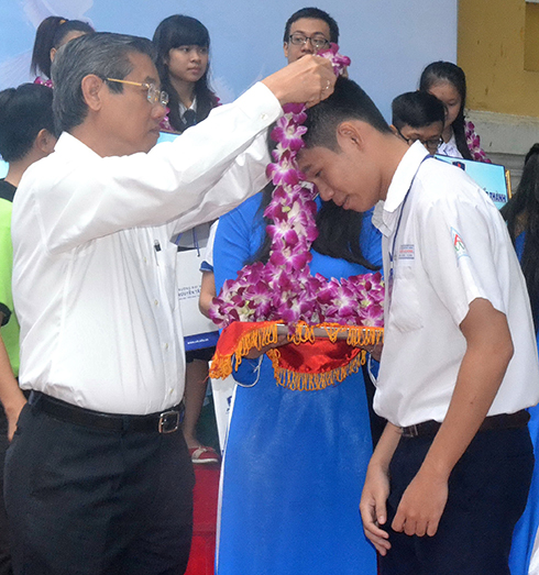 Ông Hứa Ngọc Thuận, phó chủ tịch UBND TP.HCM, đeo vòng hoa, chúc mừng các học sinh tiêu biểu làm theo lời Bác - Ảnh: Q. Phương