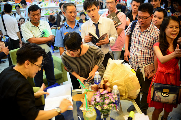 Ns Thành Lộc ký tặng cho bạn đọc. Hàng trăm đọc giả xếp hàng chờ được ký tặng và chụp ảnh chung với thần tượng của mình - Ảnh: TTD