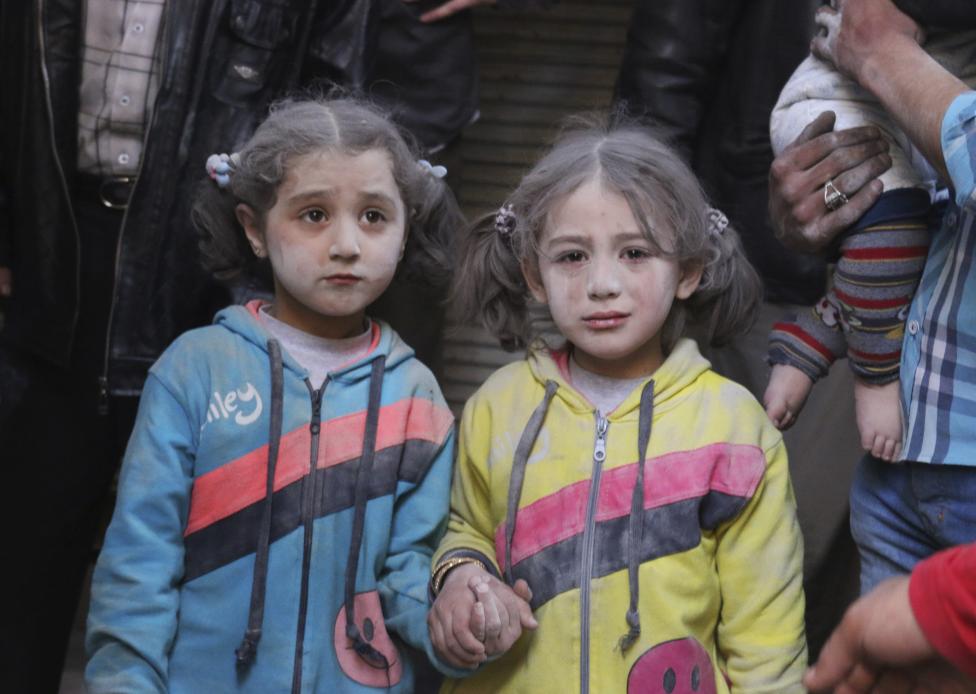Hai bé gái sống sót nắm chặt tay nhau sau một vụ tấn công tên lửa đất đối đất tại quận Bab al-Hadeed, thành phố Aleppo ở Syria ngày 7-4-2015. Các nhà hoạt động cho rằng cuộc tấn công được gây ra bởi các lực lượng trung thành với Tổng thống Bashar al-Assad - Ảnh: Abdalrhman Ismail