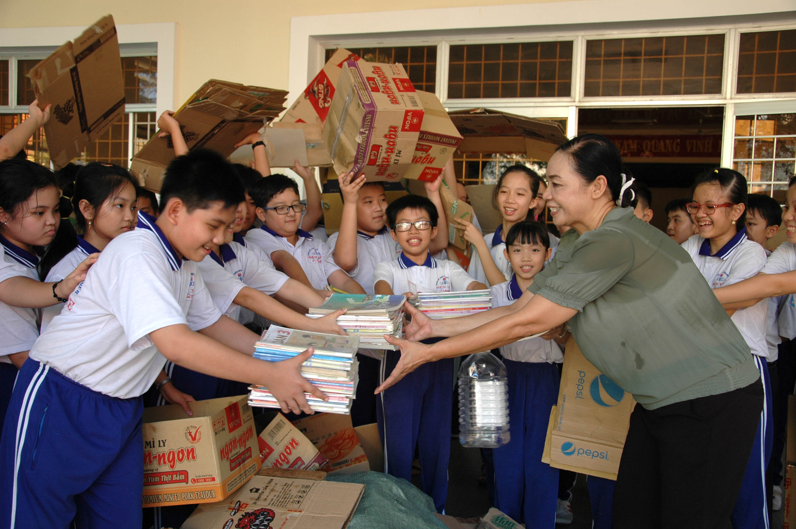 Các em học sinh hào hứng nộp phế liệu và gửi sách cũ cho cô giáo, để tặng cho những bạn học sinh có hoàn cảnh gia đình khó khăn - Ảnh: Lư Thế Nhã