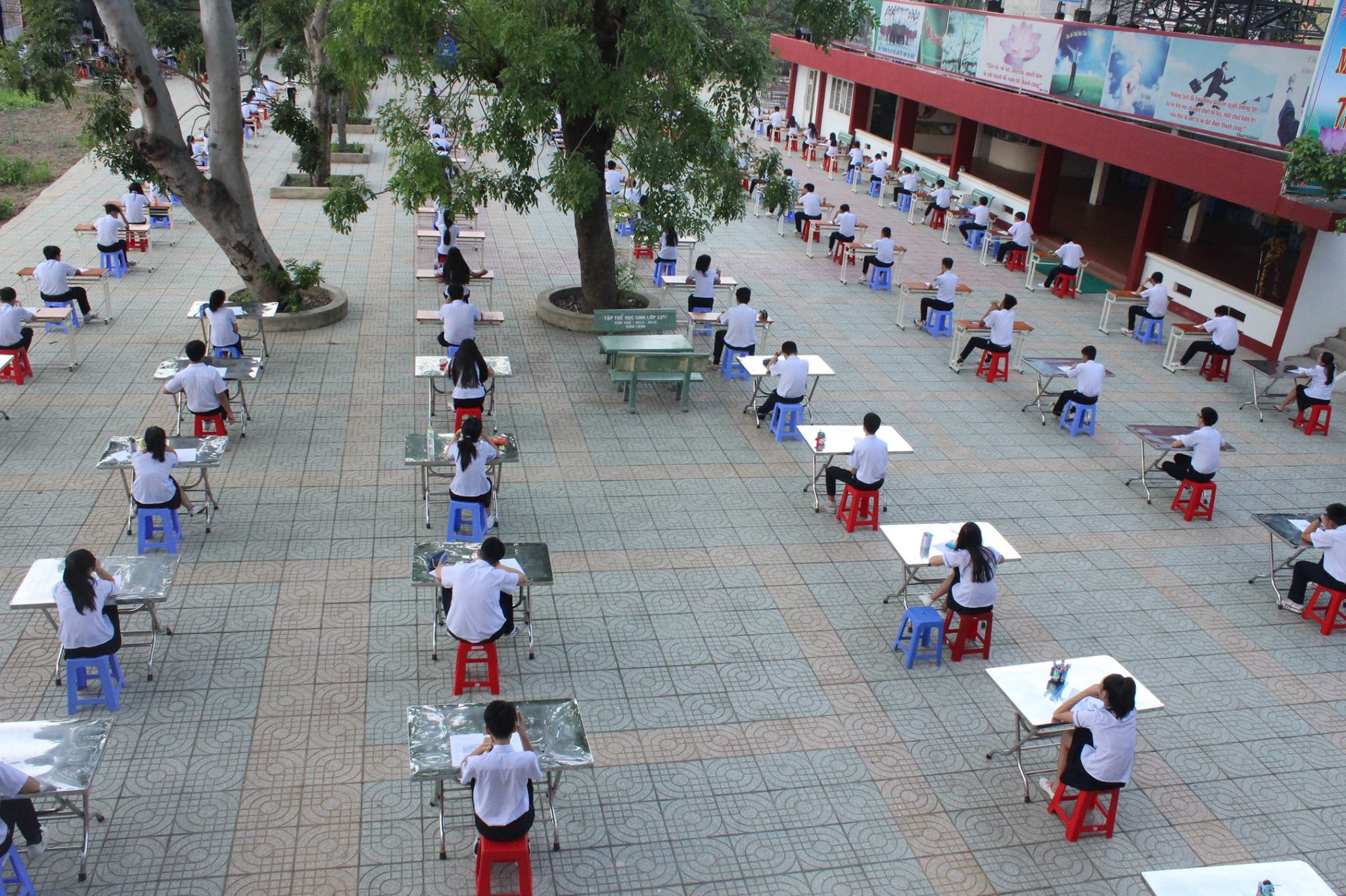 Học sinh Trường THPT An Dương Vương (TP.HCM) làm bài kiểm tra ở sân trường - Ảnh: từ Facebook của Trường THPT An Dương Vương