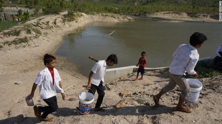 Ba cậu bé Campuchia đang xách nước để sử dụng cho nhà vệ sinh trong trường - Ảnh: CNN